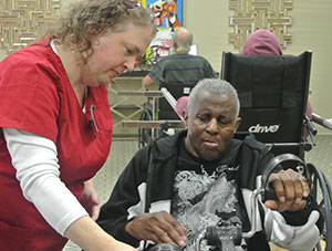 therapist working with elderly man on rehabilitation equipment