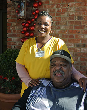 staff member and resident in a wheelchair smiling for the camera